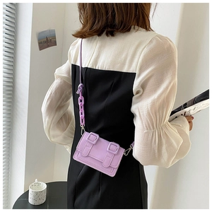 Detail view of mini purple crossbody bag with chunky chain strap on model's back