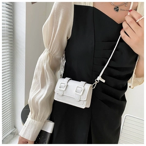 Detail of a white mini faux leather crossbody bag with stylish double ring buckle design