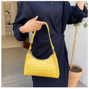 Detail shot of bright yellow faux leather underarm bag with crocodile embossed texture