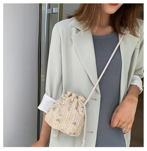 Détail du sac seau en paille tissé à la main avec broderie florale et cordon serrage