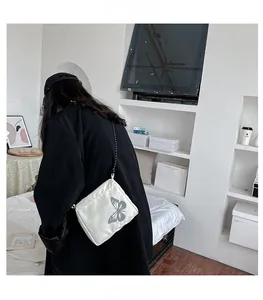 Rear view of a model wearing a white square crossbody bag with reflective butterfly print