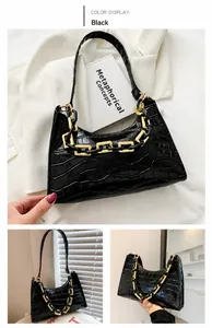 Detail of black crocodile pattern baguette bag with chunky golden chain strap