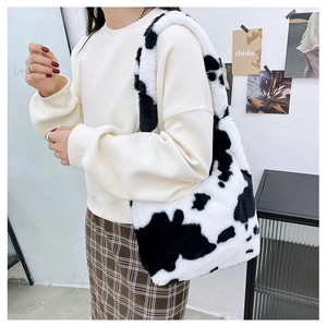 Close-up of fluffy cow print tote bag showing plush faux fur texture and shoulder strap