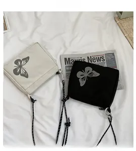 Detail view of black and beige crossbody bags with reflective butterfly print and woven straps