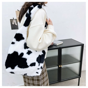 Model wearing a large plush cow print tote bag with soft faux fur texture for autumn