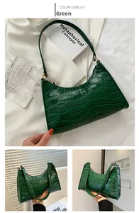 Detail of green crocodile embossed leather shoulder bag with sleek gold hardware finish