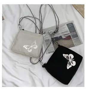 Detail of grey and black oxford fabric crossbody bags with reflective butterfly embroidery