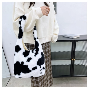 Furry shoulder bag with cow print pattern worn by a model in a stylish indoor setting