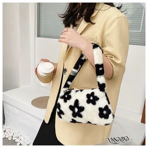 Detalle de bolso bajo el brazo de felpa con estampado floral negro y blanco suave