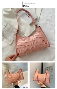 Detail of pink faux leather shoulder bag featuring crocodile pattern and top metal zipper