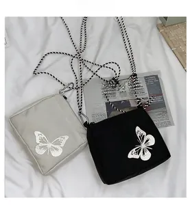 Detail of waterproof nylon crossbody bag featuring reflective butterfly and checkered strap