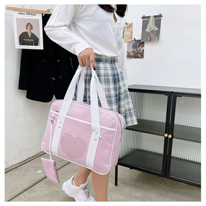 Detailed close-up of a pink JK uniform travel bag with heart stitching and small accessory