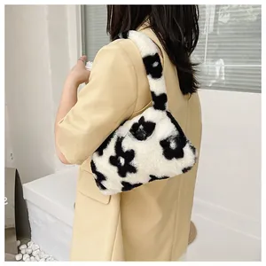 Detalle de bolso de axila de felpa blanca con flores negras y correa de hombro suave