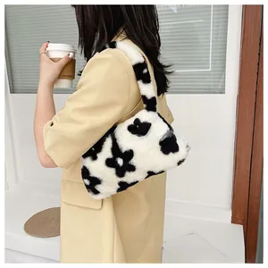 Detalle del bolso floral de felpa con patrón de flores blancas y negras en piel sintética