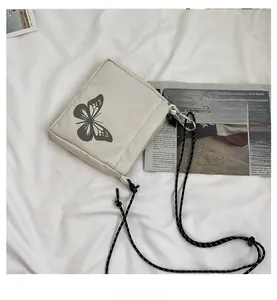 Detail of off-white crossbody bag featuring black butterfly print and cord strap