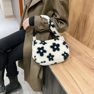 Dettaglio borsa sottobraccio in peluche floreale indossata con un trench coat kaki lungo