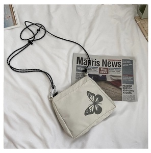 Detail of white nylon crossbody bag featuring reflective butterfly print and braided rope strap
