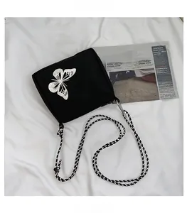 Detail of black oxford cloth crossbody bag featuring reflective butterfly print and rope strap