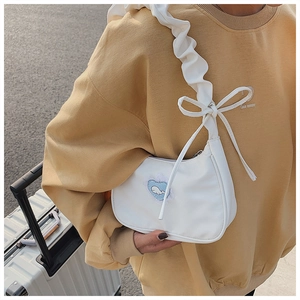 Close-up of white canvas shoulder bag with ruffle strap and cute whale embroidery detail