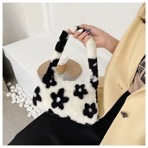 Detalle de bolso de hombro de felpa con elegante patrón de margaritas blancas y negras