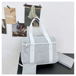Detail view of light gray tote bag with heart-shaped clear pocket and matching pouch
