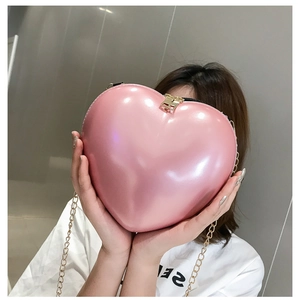Detailed view of a pink heart-shaped mini chain bag with metallic finish and gold zipper