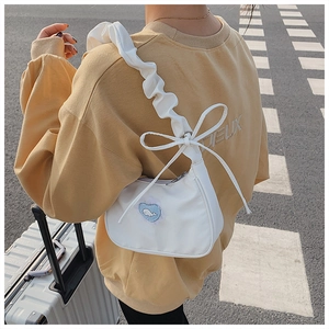 Detail of white canvas crossbody bag with pleated strap and blue heart whale patch