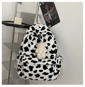 Dettaglio dello zaino in peluche maculato bianco e nero con ciondolo a forma di orsetto