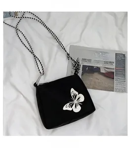Close-up of black crossbody bag with reflective butterfly print and woven strap details