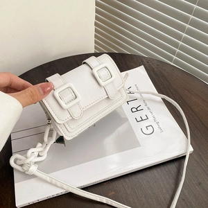 Minimalist white mini crossbody bag with double buckle design on a wooden table