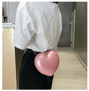 Model view showing the pink heart-shaped mini chain bag worn as a shoulder purse