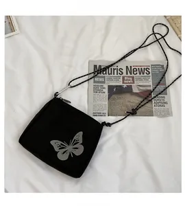 Detail of a black square crossbody bag with a butterfly print and metal carabiner hook