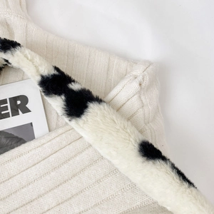 Détail du tricot blanc avec bandoulière en fausse fourrure pelucheuse à pois noirs