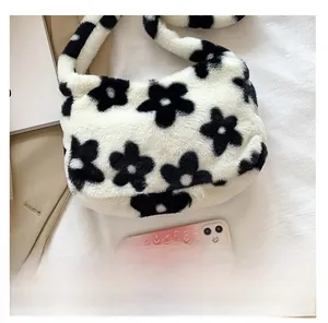 Détail du sac sous le bras en fausse fourrure avec motif vache et téléphone pour échelle