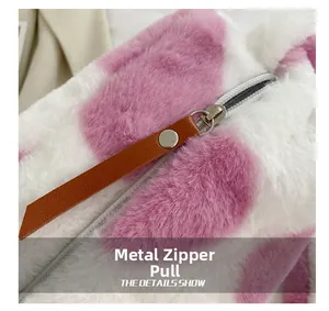 Details des Silber-Metall-Reißverschlusses und braunen Kunstleder-Ziehers am Kunstfell