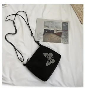 Detail of black crossbody bag featuring a reflective butterfly print and cord strap