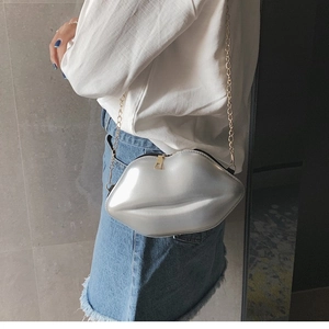 Chic silver lip-shaped crossbody bag with gold chain strap worn by model in minimalist style
