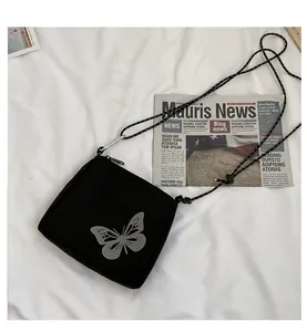 Detail view of black oxford fabric crossbody bag featuring reflective butterfly print