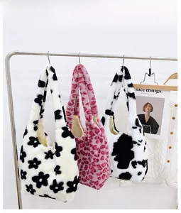 Various plush faux fur shoulder bags in leopard and cow patterns hanging on a metal rack