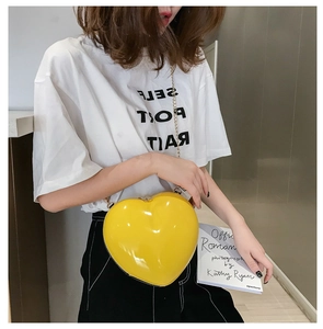 Detail view of bright yellow heart-shaped crossbody bag with gold chain strap