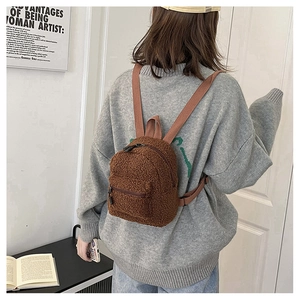 Detailed back view of a brown plush mini backpack worn over a grey sweater on one shoulder