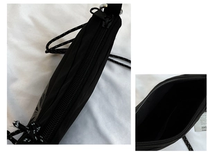 Close-up of the black nylon crossbody bag showing the zipper and tree logo detail