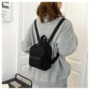 Mini black fleece backpack with cute plush bunny ears worn by a model in a minimal setting