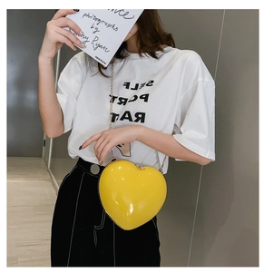 Close-up of bright yellow heart-shaped chain bag with high-gloss mirror finish and metal clasp