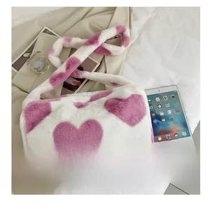 Detailaufnahme der flauschigen weißen Plüschtasche mit rosa Herzmuster auf hellem Bettzeug