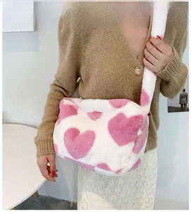 Detail einer weichen Kunstpelltasche in Weiß mit rosa Herzen und breitem Schultergurt