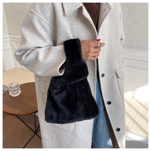 Détail du sac cabas en fausse fourrure noire montrant la texture douce et la poignée