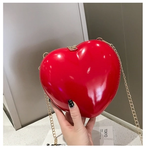 Detail view of mini red heart chain bag in shiny patent leather with gold strap