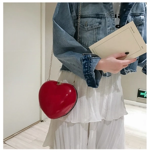 Detailed view of the red heart-shaped clutch bag with polished metallic chain strap