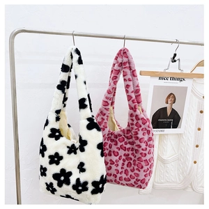 Detail view of two plush floral and leopard print tote bags hanging on a metal rack